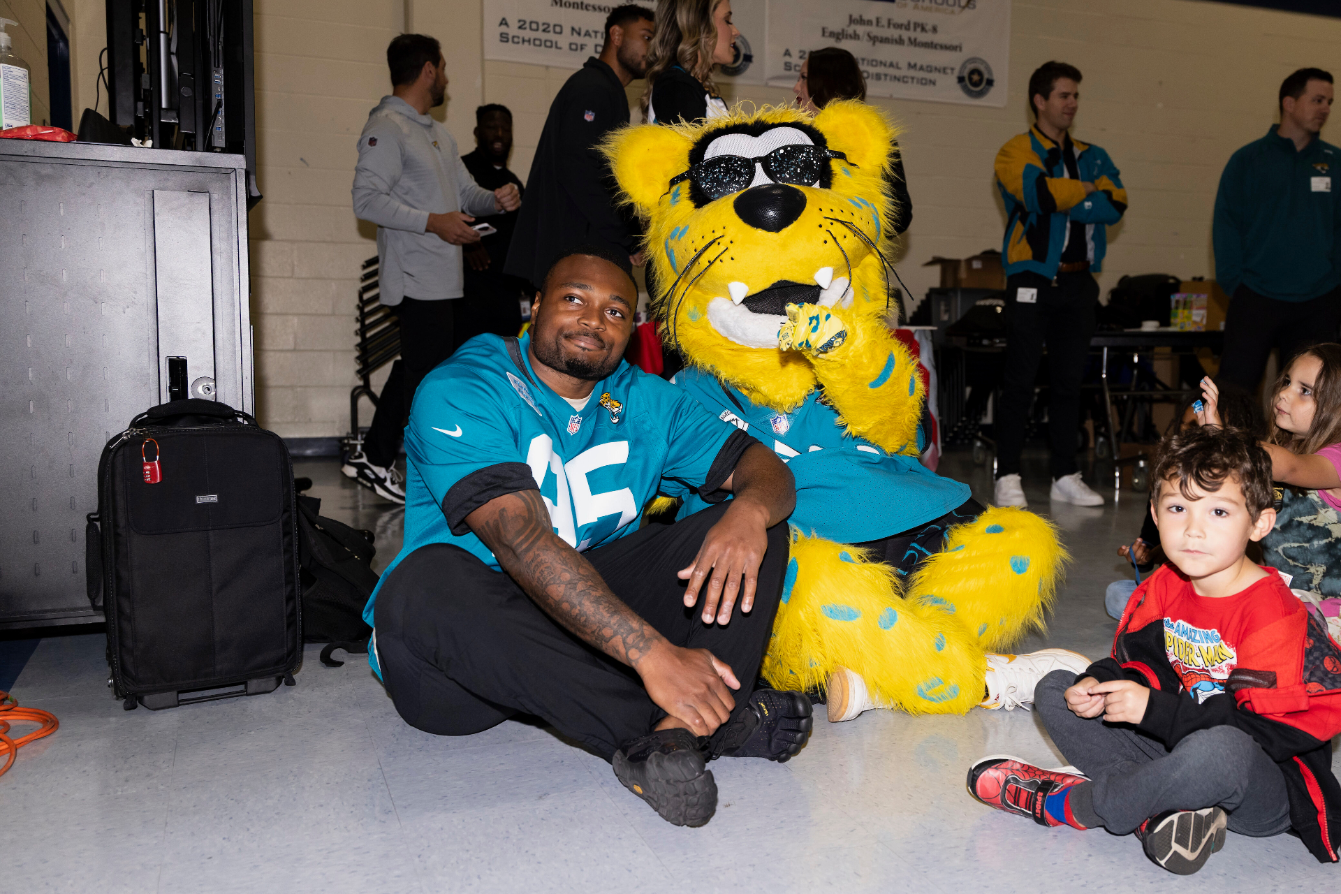 BJ Green sitting with the Jaguars mascot and a young fan